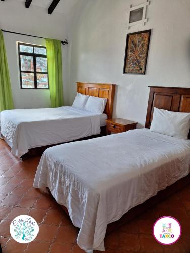 two beds in a room with green curtains at Hotel Cielito Lindo, Taxco in Taxco de Alarcón