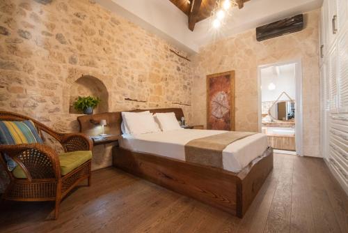 een slaapkamer met een groot bed en een stoel bij Wood and Stone Ηouse in Aegina Town