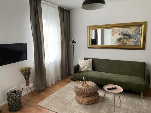 een woonkamer met een groene bank en een spiegel bij discovAIR Eisenach - 3-Zi- Apartment Matteo- Schwimmbad-Nah mit Netflix in Eisenach