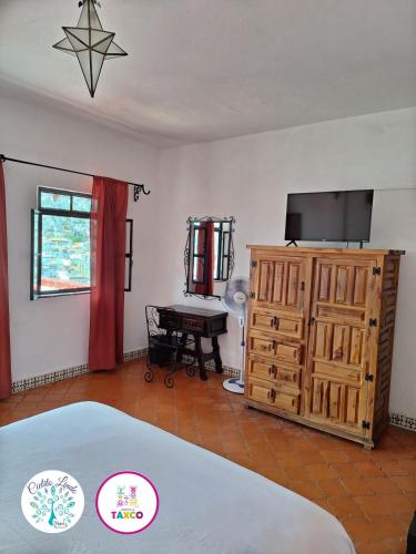 a room with a bed and a television and a desk at Hotel Cielito Lindo, Taxco in Taxco de Alarcón