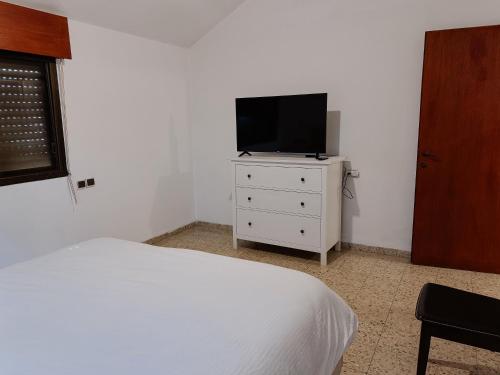 a bedroom with a bed and a television on a dresser at Salamandra Guest House מקלט פרטי in Nahariyya