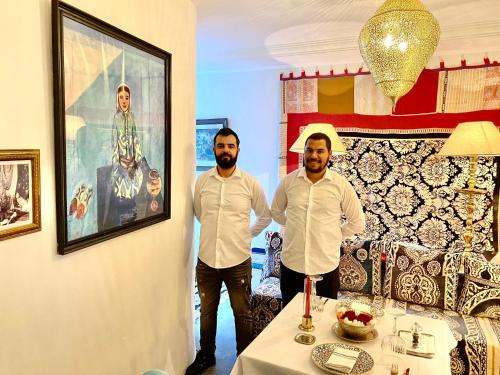 due uomini in piedi accanto a un tavolo in una stanza di Dar Nour a Tangeri