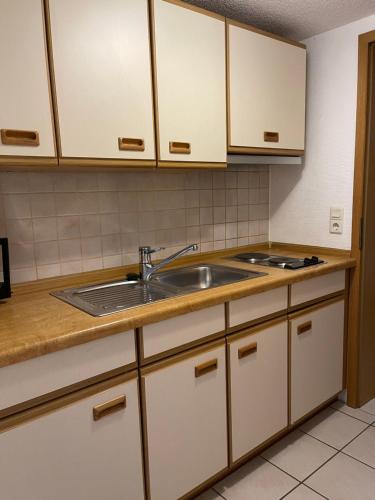 uma cozinha com armários brancos e um lavatório em Haus Sauer Bad Sassendorf em Bad Sassendorf