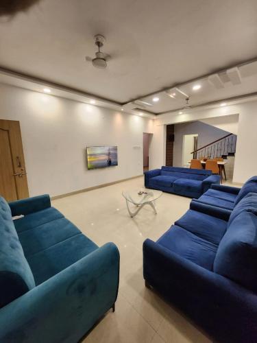 een woonkamer met blauwe banken en een tafel bij Oni Casa in Pune