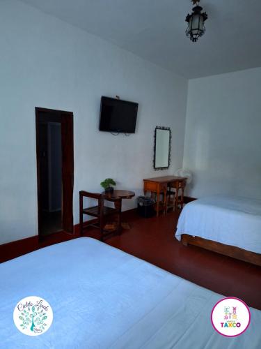 a hotel room with two beds and a flat screen tv at Hotel Cielito Lindo, Taxco in Taxco de Alarcón