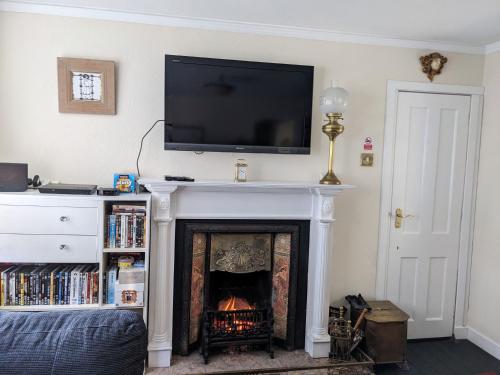 a living room with a fireplace with a tv above it at Craigmile Cottage in Fraserburgh