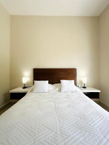 a bedroom with a large white bed with two lamps at Villas Mar Turquesa Cozumel in Cozumel
