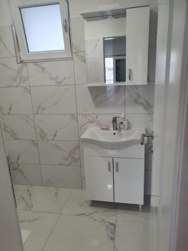 a white bathroom with a sink and a mirror at Apartments Pool Villa Maria, Novalja in Novalja