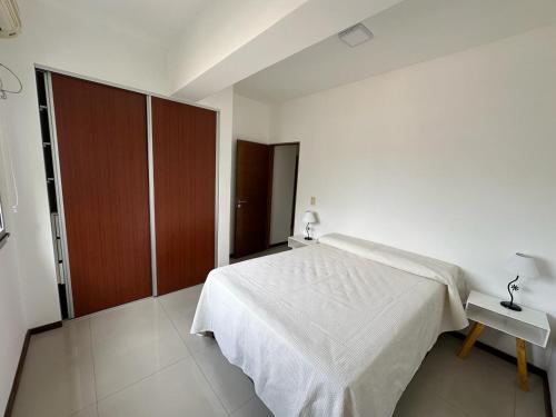 a bedroom with a white bed and a wooden cabinet at Departamento céntrico in Salta