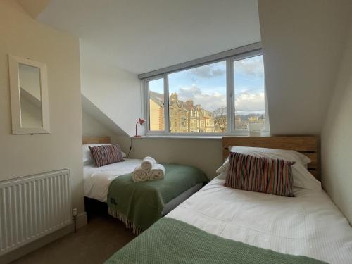 a bedroom with two beds and a large window at Ellergill in Keswick