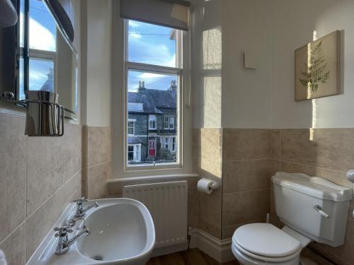 a bathroom with a toilet and a sink and a window at Ellergill in Keswick