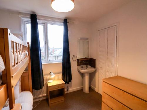 a bedroom with a bunk bed and a sink and a window at South Bay Beach House in Bridlington