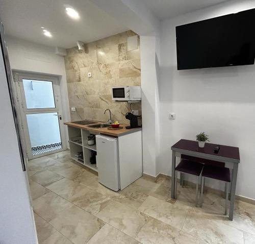 uma pequena cozinha com uma mesa e uma televisão na parede em Estudio Conil Playa em Conil de la Frontera