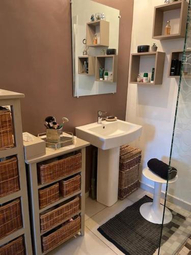 a bathroom with a sink and a mirror and baskets at Le 136 Belle Vue in Le Gosier