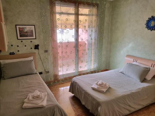 a bedroom with two beds and a window with towels at Consuelo House in Arzergrande
