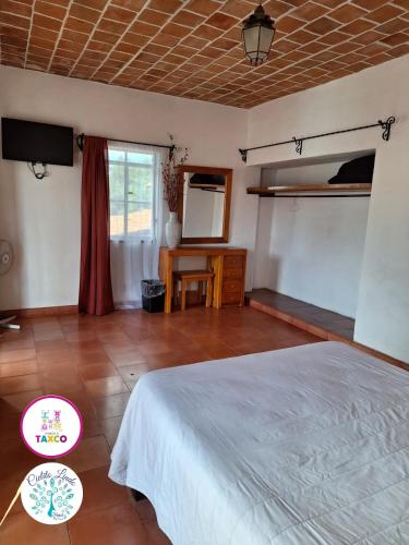 a bedroom with a bed and a table and a mirror at Hotel Cielito Lindo, Taxco in Taxco de Alarcón