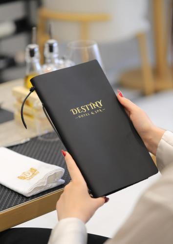 a woman holding a black book in her hands at Destiny Hotel & SPA in Tirana