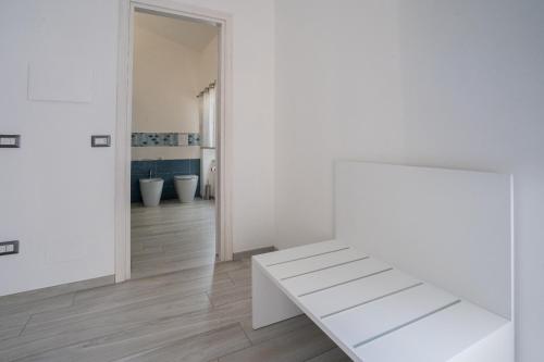 une chambre blanche avec un banc blanc et un couloir dans l'établissement Harmonia Home Capitello, à Capitello