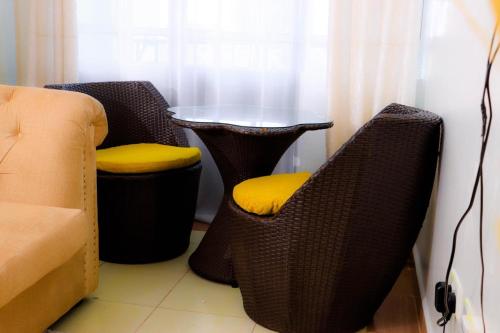 2 chaises en osier avec des sièges jaunes à côté d'une table dans l'établissement Garden estate thika road, à Nairobi