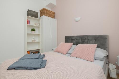 Un dormitorio con una cama con almohadas rosas. en Apartament Mewa en Dziwnówek