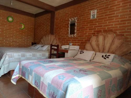 1 dormitorio con 2 camas y pared de ladrillo en Hotel Villas Kerendarhú, en Bernal