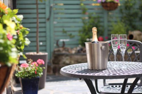 een fles champagne in een emmer op een tafel met wijnglazen bij Ginentonic Holiday Cottage in Saint Keverne