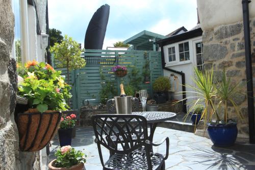 a patio with a table and chairs and potted plants at Ginentonic Cottage in Saint Keverne