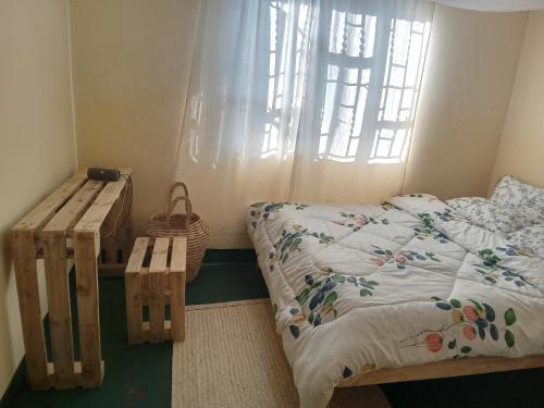 1 dormitorio con cama, banco y ventana en Arusha-paradise-home, en Nkoanrua