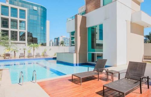 una piscina con 2 sillas junto a un edificio en Bloco A AP 310 · Hotel Jade, Park Sul vista livre en Brasilia