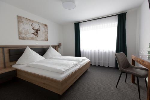 a bedroom with a bed and a desk and a window at Pension Landgasthof Schützen in Tengen