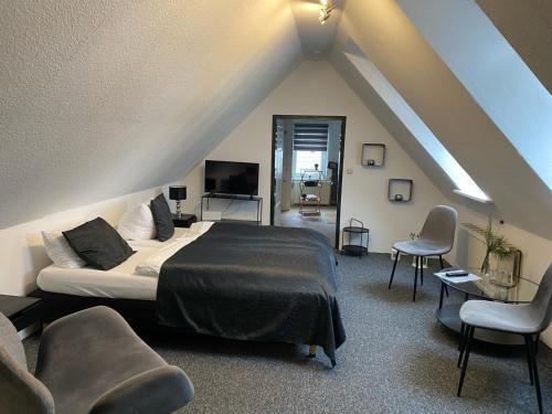 ein Schlafzimmer mit einem Bett und Stühlen im Dachgeschoss in der Unterkunft Altstadt-Hotel Gosequell in Goslar