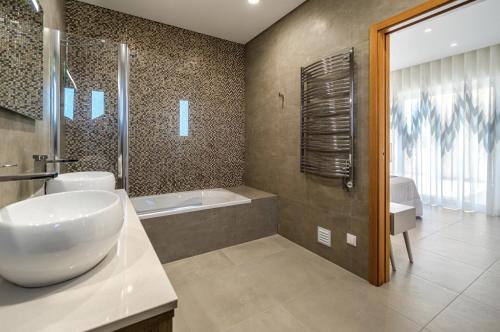 a bathroom with a sink and a shower and a tub at Holiday House Beach Porto Mós by Villas Key in Lagos