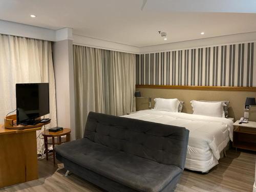 a hotel room with a bed and a couch at Suite Radisson Vila Olimpia in Sao Paulo