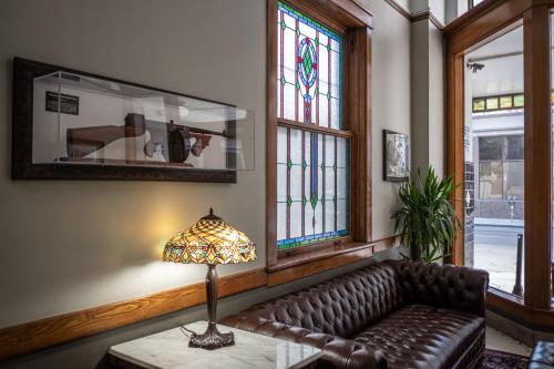 a living room with a leather couch and stained glass windows at Gardner Hotel & Hostel in El Paso