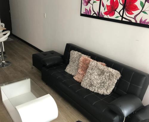 a black couch with two pillows on it in a living room at Apartamento central in Manizales