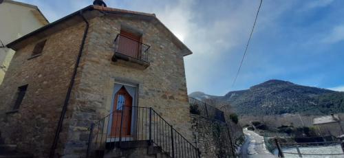 um edifício de pedra com uma porta vermelha numa montanha em Casa Castillón em Ceresa