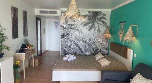ein Wohnzimmer mit einem Sofa und einem Wandbild in der Unterkunft Couleur caraïbes appartement dans un hôtel 3 étoiles vue mer in Sainte-Luce