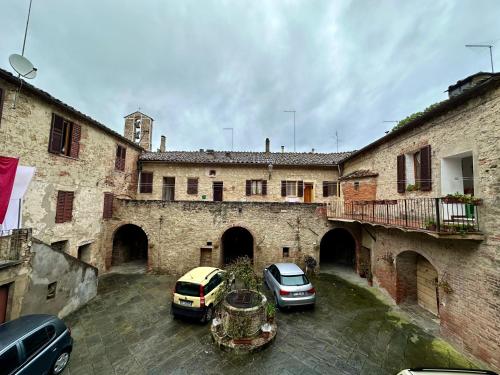 twee auto's geparkeerd op een binnenplaats in een gebouw bij La casina nel convento in Asciano