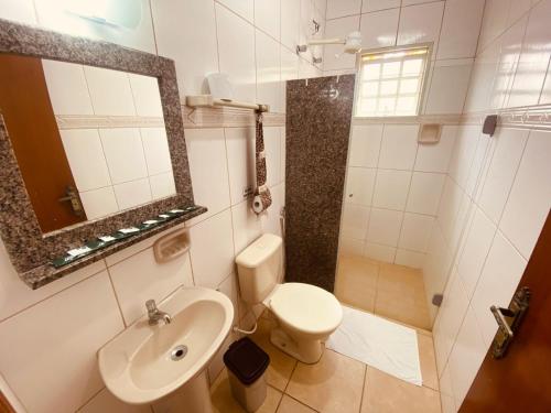 a bathroom with a sink and a toilet and a mirror at Pousada Jovimar in Aparecida