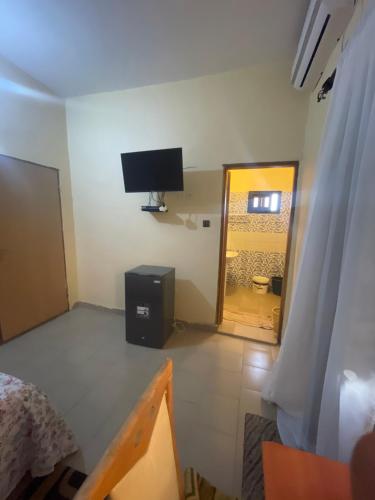 a room with a tv on the wall and a bedroom at Diabir in Ziguinchor
