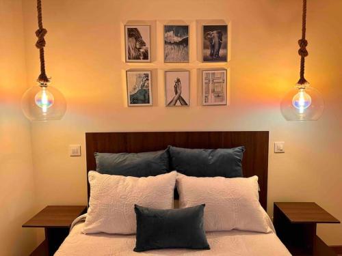 um quarto com uma cama com 2 candeeiros e fotografias na parede em la Casina Lopez em Cudillero