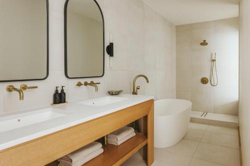 a bathroom with a sink and a tub and a mirror at Drift Nashville, a Member of Design Hotels in Nashville