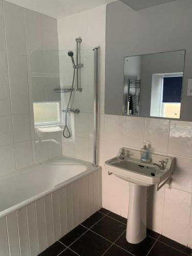 a white bathroom with a sink and a shower at Tenby Cottage with Parking in Tenby