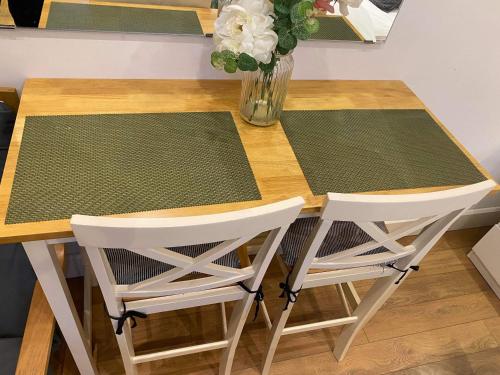 a dining room table with two chairs and a vase of flowers at Studio apartment near Sutton, Croydon in Banstead