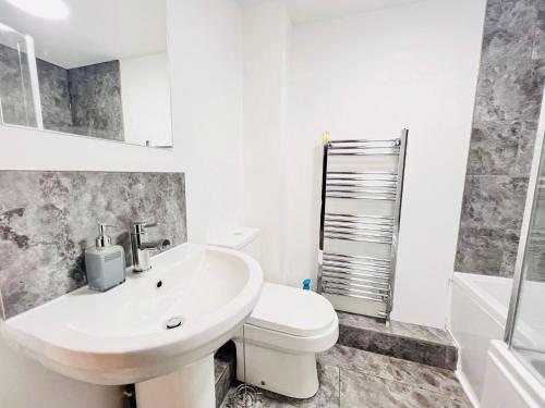 a white bathroom with a toilet and a sink at Brand New 2 Bedroom Apartment with Wi-Fi Sleeps 4 - Tanzanite in Cambridge