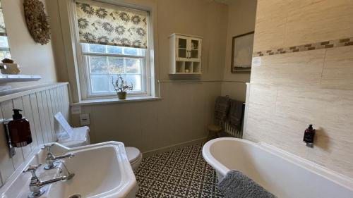 a bathroom with a tub and a toilet and a sink at Tan Y Cytiau in Holyhead