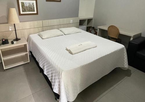 een slaapkamer met een wit bed en 2 handdoeken bij Pousada Tropical in Barra do Garças