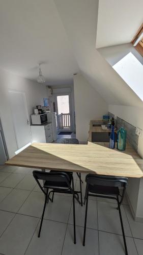 a large wooden table in a kitchen with two chairs at L'appart le “BapTho” in Cléder