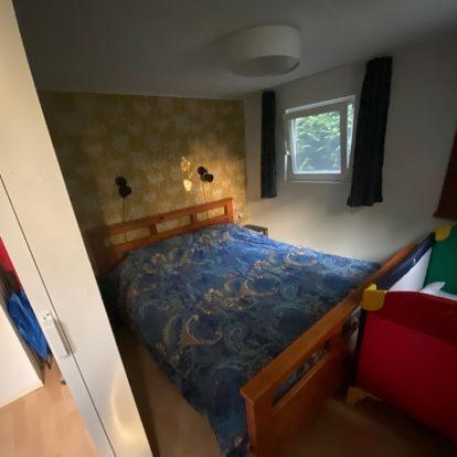 een kleine slaapkamer met een bed met een blauw dekbed bij Het Bruggetje Leekstermeer in Matsloot