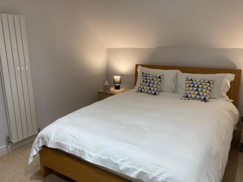 a bedroom with a large white bed with pillows at Downs Cottage in Bristol